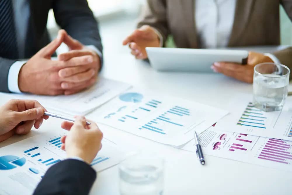 a group of people sitting around a table with papers and graphs : showing projects growth graph of Rank Stride